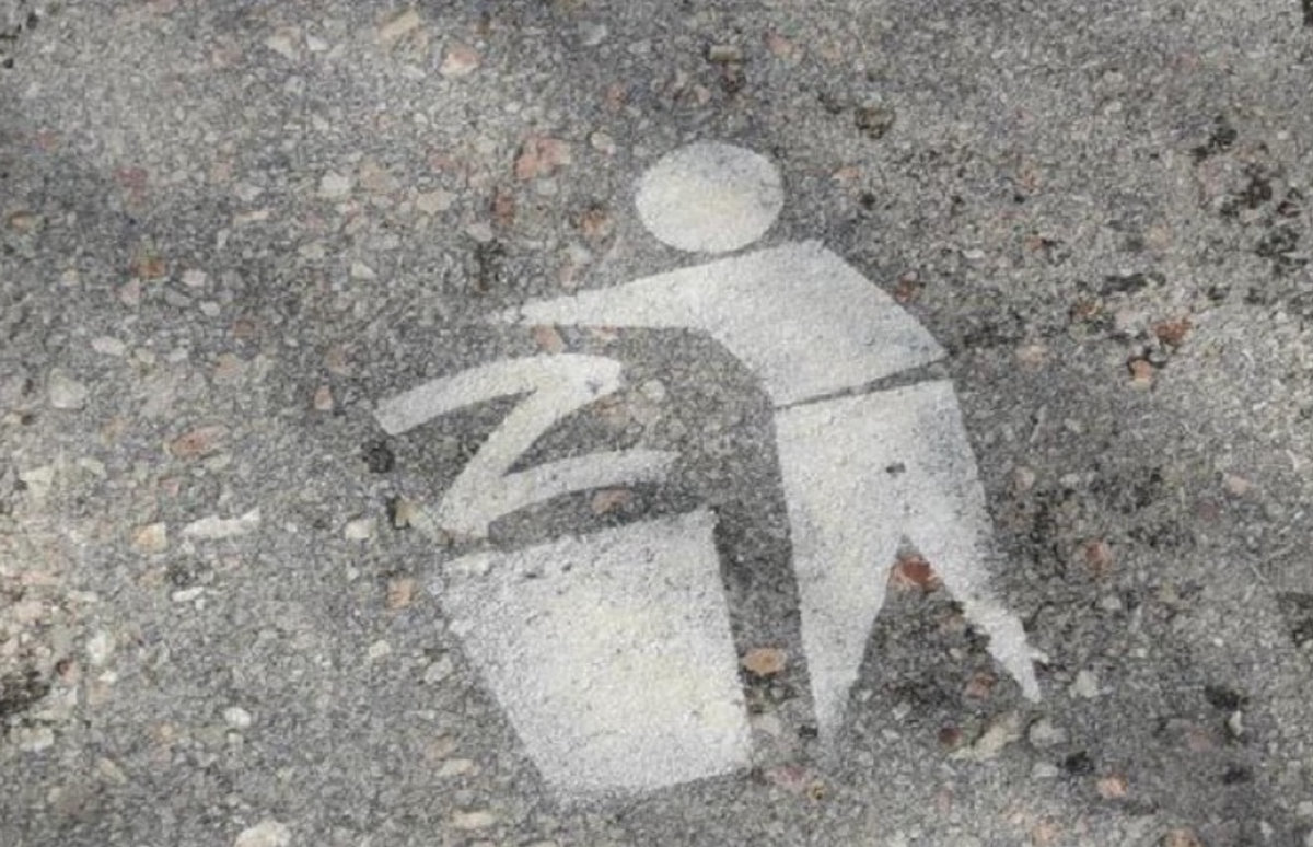 spray-painted figured dropping a "Z" (symbol of Putin's invaders) in a waste bin